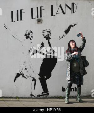 Une femme prend un en face de selfies un morceau de street art par l'artiste Bambi, intitulé mentir mentir Land - représentant le premier ministre Theresa mai et le président américain, Donald Trump, dansant dans une pose parodiant le film La La Land - à Islington, Londres. Banque D'Images