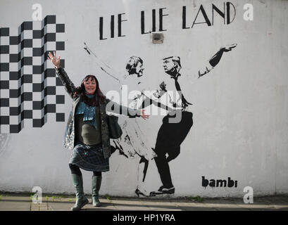 Une femme frappe un posent devant un morceau de street art par l'artiste Bambi, intitulé mentir mentir Land - représentant le premier ministre Theresa mai et le président américain, Donald Trump, dansant dans une pose parodiant le film La La Land - à Islington, Londres. Banque D'Images