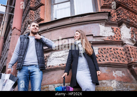 Man and Woman holding parapluies dans un jour de vent et de rire dans le contexte d'une maison ancienne. Banque D'Images