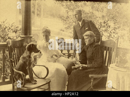 C Antique1890 photographie, groupe d'adultes de l'époque victorienne sur porche avec chien. Emplacement : New England, USA. SOURCE : tirage photographique original. Banque D'Images