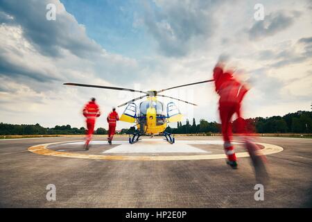 Alarme pour l'air rescue service. Équipe de sauveteurs (paramédic, médecin et pilote) fonctionnant à l'hélicoptère sur l'héliport. Banque D'Images