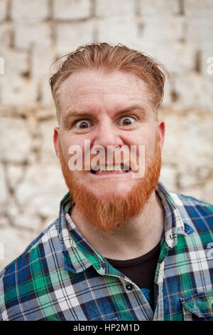 Portrait d'homme aux cheveux rouge hipster avec chemise à carreaux bleu exprimant une émotion Banque D'Images