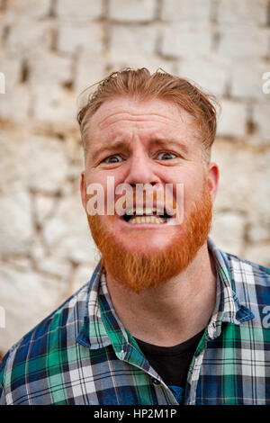 Portrait d'homme aux cheveux rouge hipster avec chemise à carreaux bleu exprimant une émotion Banque D'Images