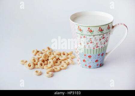 Les flocons de maïs et le lait dans la tasse sur un fond blanc. Banque D'Images