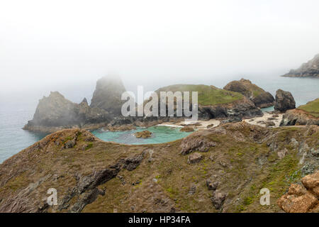 Plage de sable fin avec une mer turquoise waters cachés dans rocky shore sur l'été un jour brumeux, Cornwall, lézard, presqu'île, le sud-ouest de l'Angleterre Banque D'Images