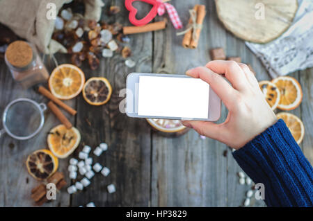 Smartphone est sur le bras droit, l'homme photographies la nourriture sur une table grise, vue d'en haut Banque D'Images