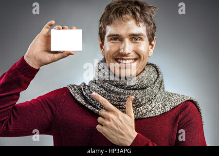 Smiling man enveloppé dans une écharpe, holding box pour la médecine. Photo de l'homme malsain face à l'emballage blanc pour la médecine. Concept de soins de santé Banque D'Images