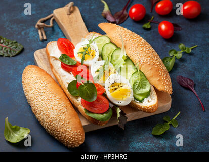 Petit-déjeuner diététique. Pain avec du fromage cottage, avec tomate, concombre, oeuf dur, les verts sur fond bleu Banque D'Images