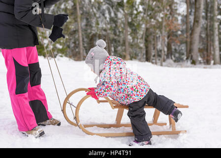 Plein air hivernales en famille ; une maman avec ses filles sur un traîneau Banque D'Images