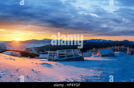 Magnifique coucher de soleil au-dessus des montagnes enneigées et des chalets en bois Banque D'Images