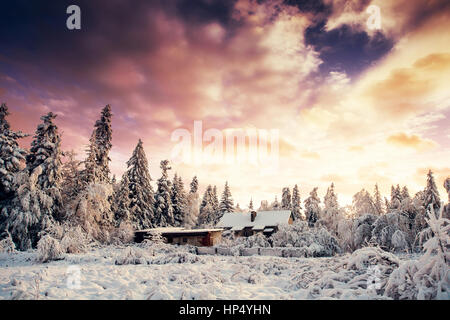 Magnifique coucher de soleil au-dessus des montagnes enneigées et des chalets en bois Banque D'Images