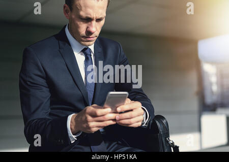 Confiant handsome businessman en utilisant son téléphone. L'intérieur horizontal tourné Banque D'Images