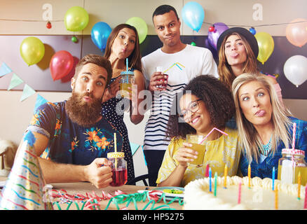 Amis de Goofy faces stupides tirant alors que la fête célébrant un anniversaire avec des ballons et décorations de fête Banque D'Images