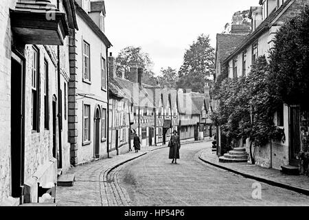 Une dame marcher au milieu d'une assez Warwick road portant un sac. Au loin une autre dame marche sur le trottoir, trottoir, loin de l'appareil photo. Photographie prise dans les années 1940, restauré à partir d'une numérisation à haute résolution prises par le négatif original. Banque D'Images