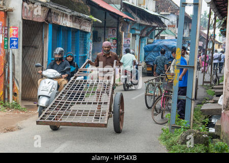 Mumbai, Inde - 11 décembre 2016 - l'homme tirant une charrette dans les rues bondées et la circulation à Mumbai avec les tuk tuk et les taxis Banque D'Images