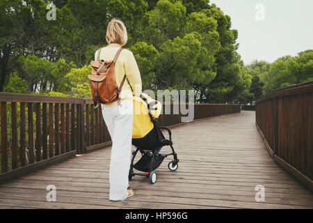 Jeune mère se promener avec nouveau-né dans le chariot sur pont de bois dans la région de Green Park Banque D'Images