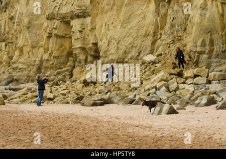 West Bay, Dorset, UK. 19 février 2017. Météo britannique. 3 Les jeunes visiteurs à la station balnéaire de la baie de l'Ouest risquent leur vie en grimpant sur le terrain à l'East Cliff de West Bay, de sorte que leur père peut prendre une photo d'eux. Au cours des dernières années leur ont été nombreux Glissements et chutes de pierres le long des falaises de West Bay à Burton Bradstock avec un décès en 2012. Crédit photo, Graham Hunt/Alamy Live News Banque D'Images