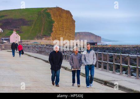 West Bay, Dorset, UK. 19 février 2017. Météo britannique. Les gens qui marchent le long de la promenade à la recherche au coucher du soleil au large de la côte de la baie de l'Ouest dans le Dorset après une journée au-dessus de la moyenne des températures et un ciel nuageux. Crédit photo : Graham Hunt/Alamy Live News Banque D'Images