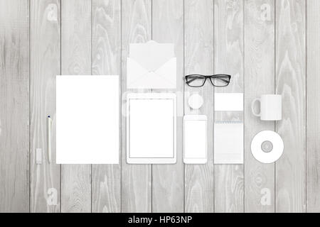 Maquette stationnaire inclut des papiers, sketchbook, tablette, téléphone intelligent, carte de visite, un stylo, lunettes, disque compact, mug et badge pin on white background bois Banque D'Images