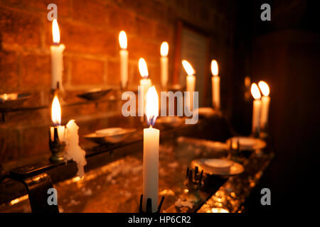 La combustion de 8 bougies blanches dans une église, l'avant-plan bougie est dans l'accent et les autres sont hors foyer, Banque D'Images