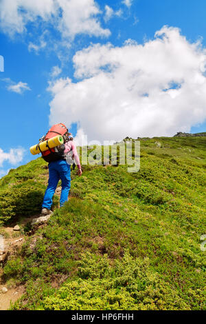 Young female hiker monter une côte. La randonnée. Randonnée dans les Carpates. Randonneur montant vers le sommet de la montagne sur un sentier très raide. Un concept de vie Banque D'Images