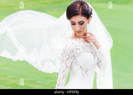 Portrait de belle mariée robe de mariage en voletant avec voile sur le champ vert du club de golf. Mariée avec long voile voletant dans le vent. Nous Banque D'Images