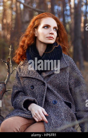 Belle femme aux cheveux rouges. Jeune fille rousse en automne vêtements de plein air. Femme rousse à l'automne en plein air PARC, portée et écharpe manteau. Regardez la mode d'automne Banque D'Images