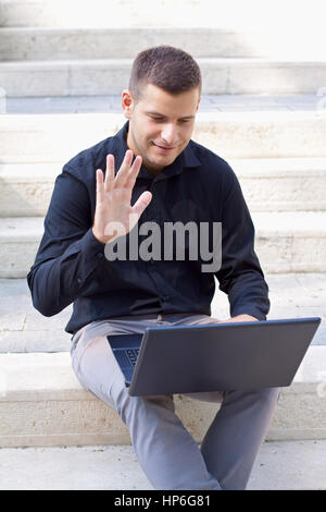 Bel homme à l'aide de son ordinateur portable dans le parc Banque D'Images