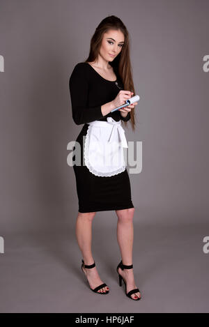 Jeune serveuse en uniforme de l'écriture d'une commande de nourriture du client Banque D'Images