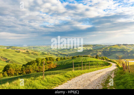 Les régions rurales de la vallée avec un paysage vallonné et un chemin de terre en Toscane, Italie Banque D'Images