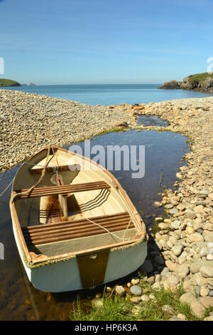 Bateau à rames solitaire sur un cours menant à une plage de galets à Pembrokeshire, Pays de Galles, Royaume-Uni Banque D'Images