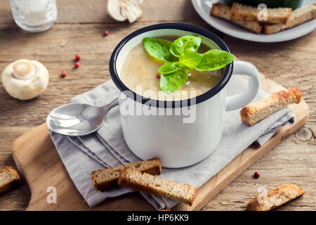 Soupe aux champignons avec des croûtons et de basilic dans la tasse en métal sur fond de bois rustique - maison bio végétalien végétarien soupe-repas délicieux déjeuner f Banque D'Images