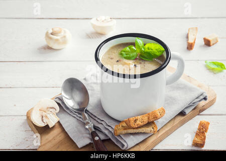 Soupe aux champignons avec des croûtons et de basilic dans la tasse en métal sur fond de bois rustique - maison bio végétalien végétarien soupe-repas délicieux déjeuner f Banque D'Images