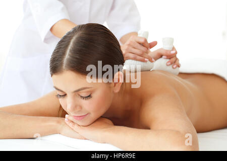 Femme dans un bain de massage avec boules de fines herbes Banque D'Images