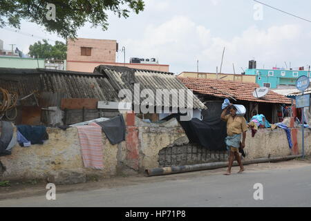 Mumbai, Inde - le 31 octobre 2015 - Homme porte paquet sur sa tête lentement en face d'un bidonville à Bombay Banque D'Images