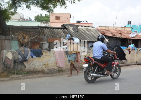 Mumbai, Inde - le 31 octobre 2015 - Homme porte paquet sur sa tête lentement en face d'un bidonville à Bombay Banque D'Images