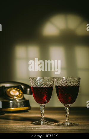 Deux verres anciens remplis de claret. Téléphone Vintage dans l'arrière-plan Banque D'Images