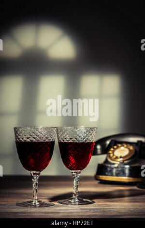 Deux verres anciens remplis de claret. Téléphone Vintage dans l'arrière-plan Banque D'Images