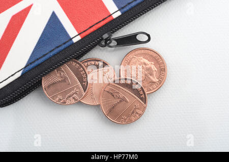 Porte-monnaie Union Jack à fermeture à glissière et pièces de monnaie britanniques débordent. Pour les dépenses des ménages, le budget, la hausse des prix, l'épargne des centimes, défi 1p. Banque D'Images