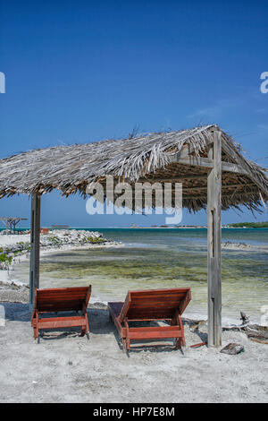 Deux fauteuils inclinables en bois sous un toit de chaume sur la plage à Bonaire Banque D'Images