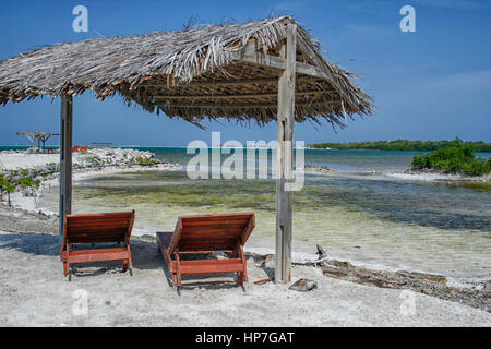 Deux fauteuils inclinables en bois sous un toit de chaume sur la plage à Bonaire Banque D'Images