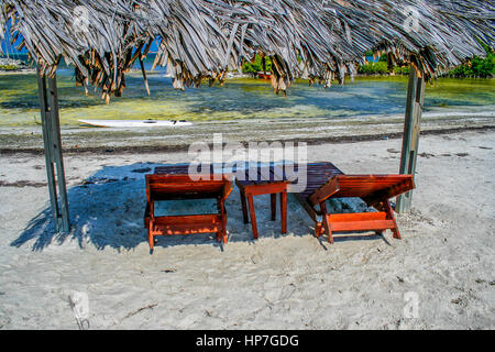 Deux fauteuils inclinables en bois sous un toit de chaume sur la plage à Bonaire Banque D'Images