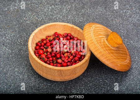 Poivre rose séchés Pois dans un bol en bois sur fond gris. Studio Photo Banque D'Images