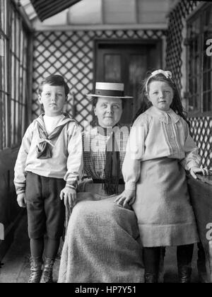 Portrait d'une mère édouardien accroupi entre ses deux jeunes enfants, vers 1905, restauré à partir d'une numérisation à haute résolution prises par le négatif original. Banque D'Images