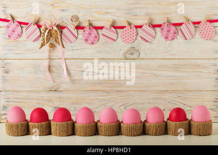 Décoration de Pâques oeufs de Pâques et les oeufs en papier, avec un ruban rose sur un fond en bois clair. Focus sélectif. Banque D'Images