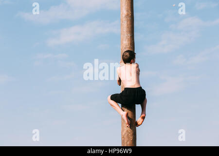 Gomel, Bélarus - Mars 12, 2016 : Jeune homme grimpe sur un poste en bois sur les traditionnelles fêtes de dédié à l'approche du printemps - célébration slaves Banque D'Images