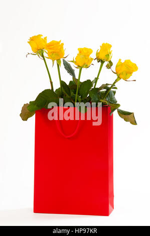 Roses jaunes bouquet dans un sac en papier rouge, isolé sur fond blanc Banque D'Images