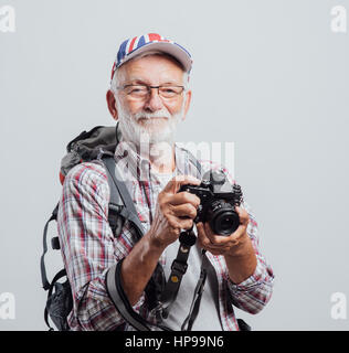 Photographe touristique principal avec sac à dos et appareil photo numérique, il porte un drapeau britannique cap Banque D'Images