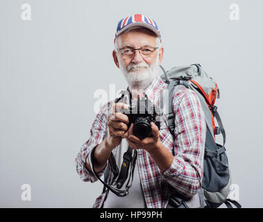 Photographe touristique principal avec sac à dos et appareil photo numérique, il porte un drapeau britannique cap Banque D'Images