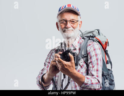 Photographe touristique principal avec sac à dos et appareil photo numérique, il porte un drapeau britannique cap Banque D'Images